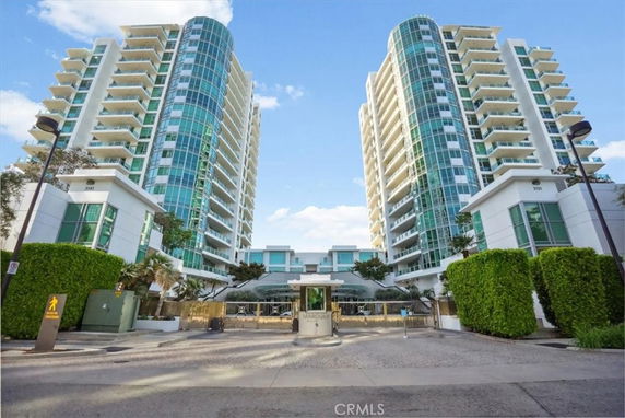 Front view of two adjacent high-rise residential buildings with balconies and glass facades.