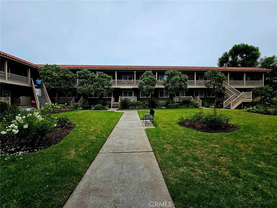 Front view of a two-story building with outdoor staircases and greenery.