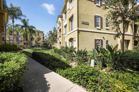 View of a multi-story residential building exterior with landscaped paths and greenery.