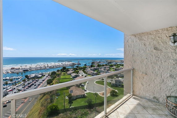 Panoramic view from a high-rise balcony overlooking the ocean and marina.