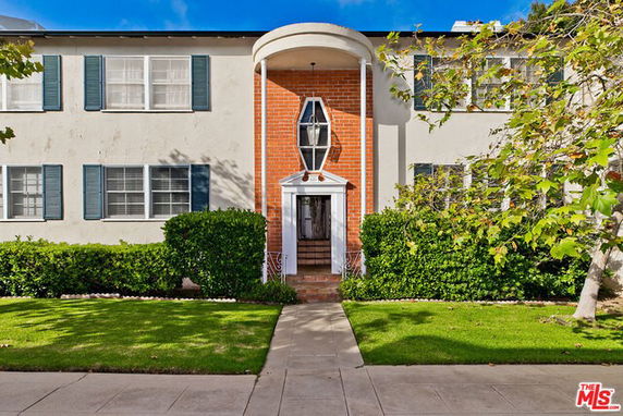 Front view of a two-story house with decorative brick entrance and blue shutters.