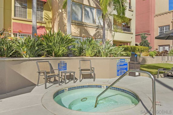 Small outdoor whirlpool with chairs around it in front of a residential building.