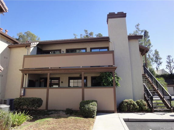 Front view of a two-story house with external staircase and chimney.