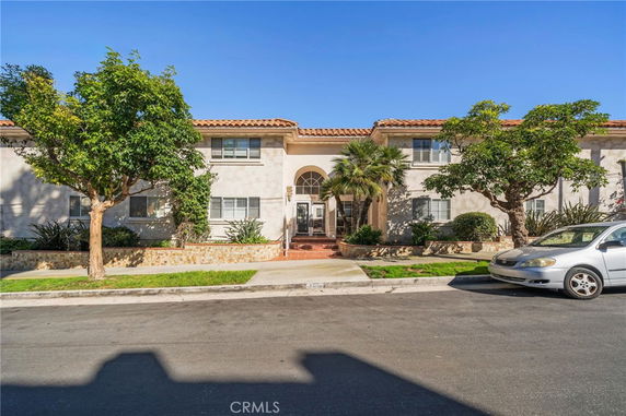 Front view of a two-story house with a central entrance and trees on either side.