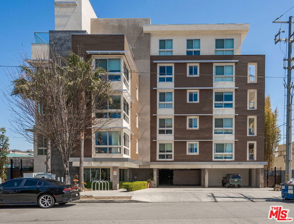 Front view of a modern multi-story apartment building with parking entrance.