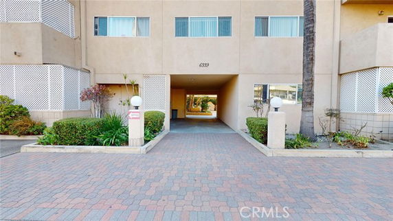 Front view of a building with a passageway and landscaped entrance.