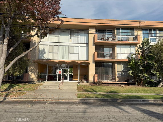 Front view of a three-story apartment building with balconies and a main entrance.