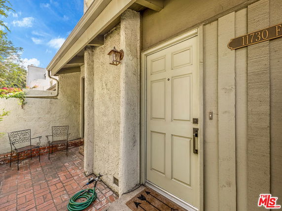 Front view of a house entrance with a white door and a small outdoor patio area.