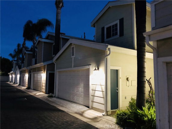 Front view of attached two-story townhouses with garages during the evening.