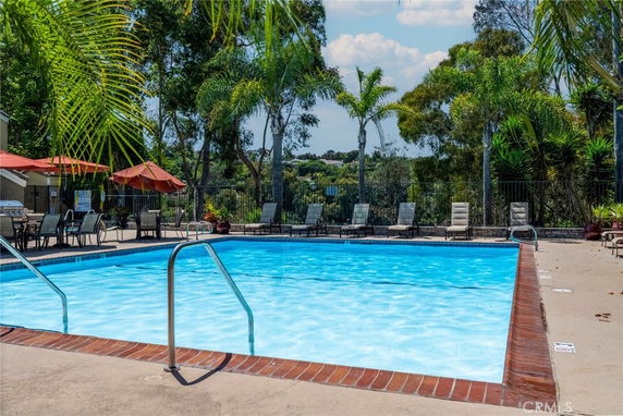 Outdoor swimming pool area with poolside chairs and umbrellas.