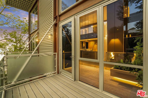 Exterior view of a modern building with glass doors and a balcony with a frosted glass railing.
