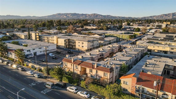 Aerial view of residential buildings and surrounding area with mountains in the background.