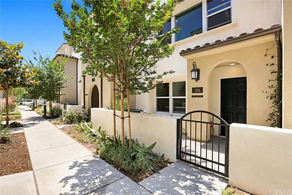 Front view of a two-story house with a gated entrance and arched doorway.
