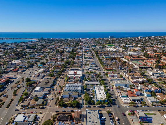 Panoramic view of a coastal city with grid-like layout and distant ocean.