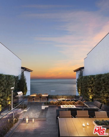 Rooftop terrace with seating and ocean view.