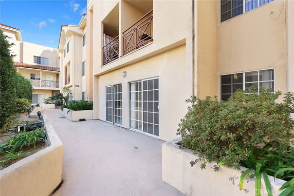 Front view of a multi-story apartment building with balconies and sliding glass doors.