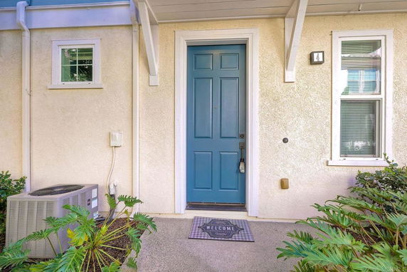 Front view of a house with a blue door and cream-colored walls.