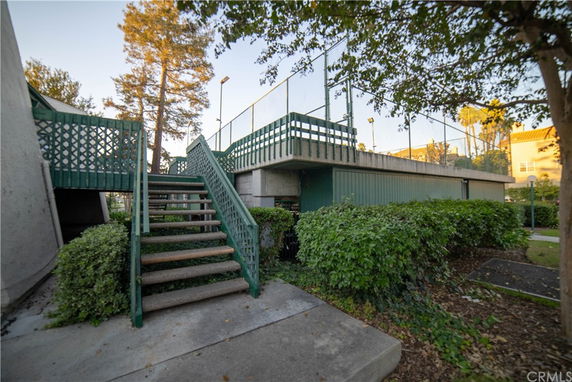 Stairs leading to an elevated outdoor area with fencing, possibly a sports court.