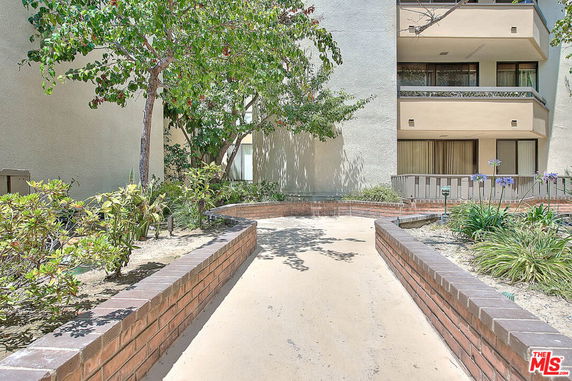 Front view of a building with balconies and surrounding landscape.