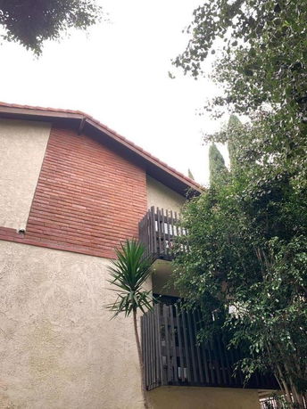Front view of a multi-story house with brick and stucco exterior and a small balcony.