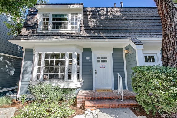 Front view of a two-story house with a gabled roof and bay windows.