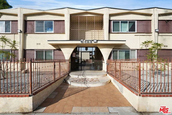 Front view of a two-story building with an arched entrance and metal fencing.