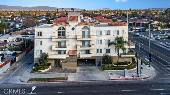 Front view of a multi-story apartment building with balconies and red-tiled roofs.