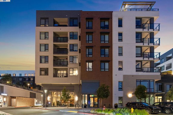 Front view of a modern multi-story apartment building with balconies.