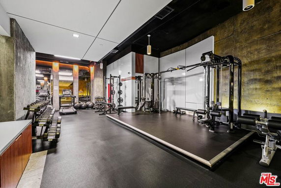 Indoor gym area with various exercise equipment including weights and machines.