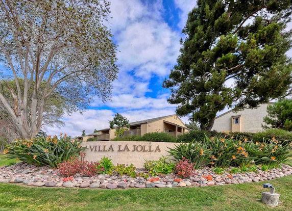View of a building with a sign that reads 'Villa La Jolla' surrounded by landscaping.