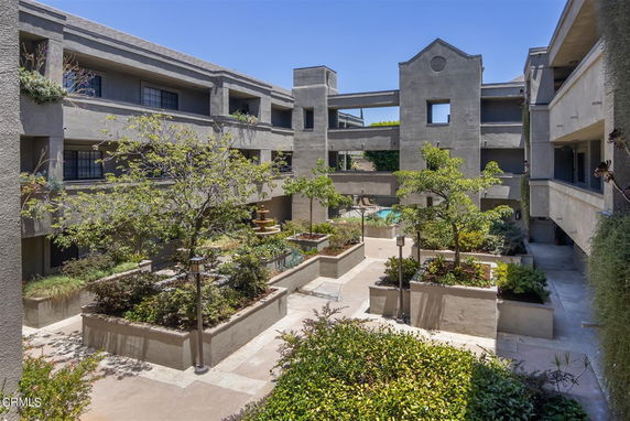 Outdoor view of apartment complex courtyard with greenery and fountain.