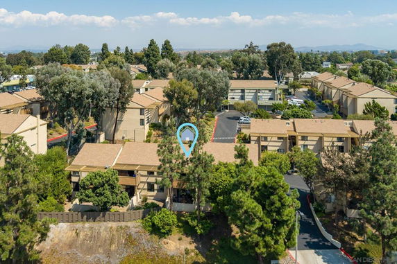 Aerial view of residential buildings with trees and roads surrounding them.
