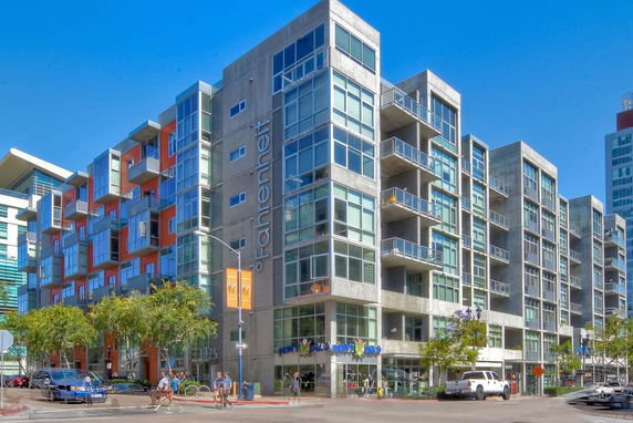 Front view of a modern multi-story apartment building with large glass windows and balconies.