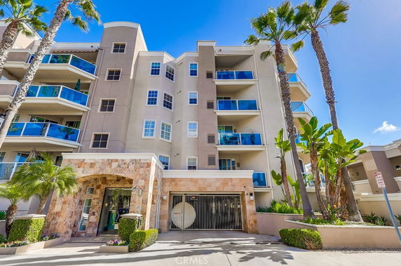 Front view of a multi-story residential building with balconies and a gated entry.