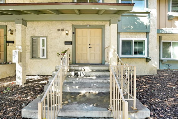 Front view of a house with a staircase leading to a double door entrance.