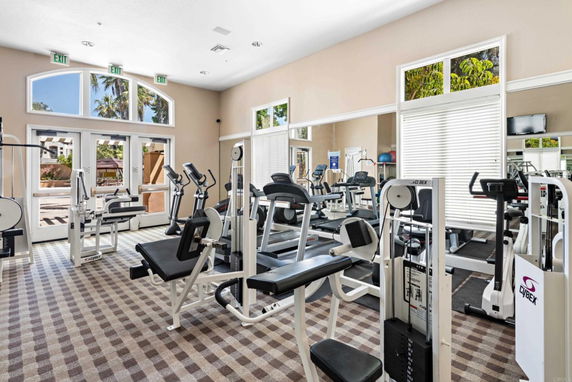 Interior view of a gym with exercise equipment and large windows.