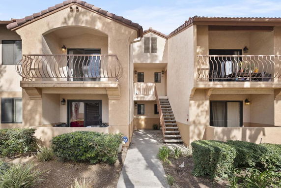 Front view of a two-story apartment building with balconies and exterior staircase.