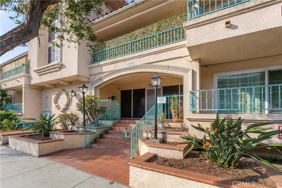 Front view of a multi-story building with a staircase entrance and balcony.
