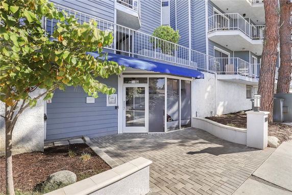 Front view of a multi-story building with balconies and a blue awning over the entrance.