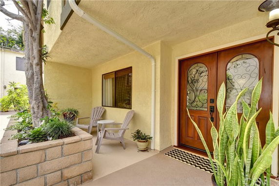 Front entrance of a house with double wooden doors and a small sitting area.