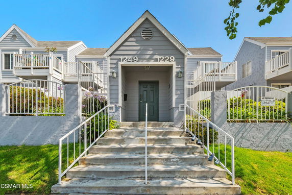 Front view of a multi-unit residential building with stairs leading to the entrance.
