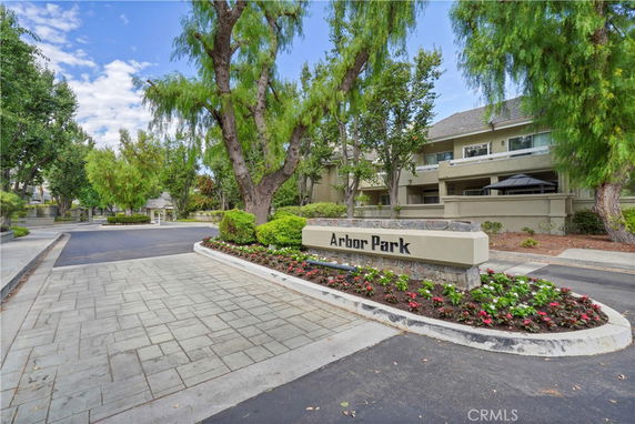 Front view of a multi-story residential building labeled 'Arbor Park' with a landscaped entrance.
