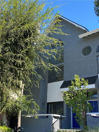 Front view of a multi-story house with a blue door and large windows.