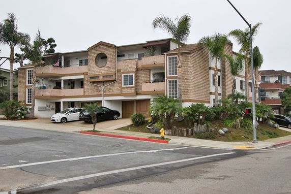 Front view of a multi-story residential building with balconies and garages.