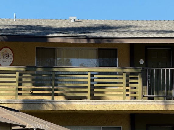 Front view of an upper-level apartment with a balcony and green railing.
