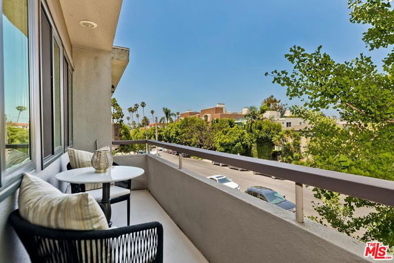 Balcony view overlooking a street with trees and distant buildings.