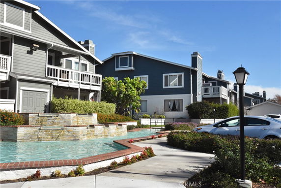 Front view of a two-story house with a balcony and water feature.