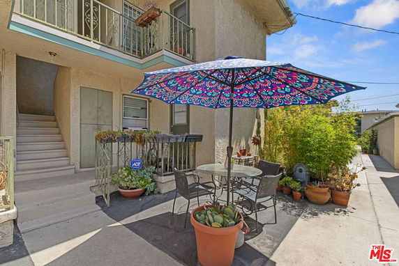 Front view of a two-story building with potted plants and outdoor seating area.