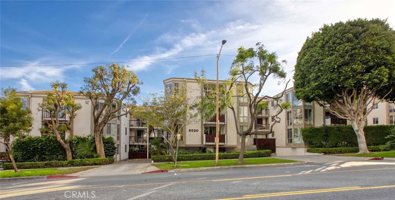 Front view of a multi-story apartment building with trees and greenery.