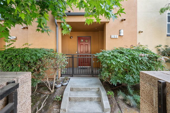 Entryway of a residential building with a red door and surrounding greenery.